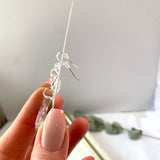 Small tear drop Queen Anne’s lace dangles on hook,
